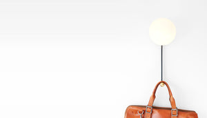 Hook sconce light on a wall with a leather satchel hanging on it
