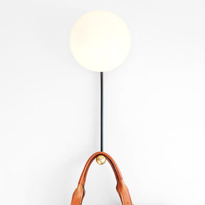 Hook Sconce is a wall light with integrated hook holding a leather satchel